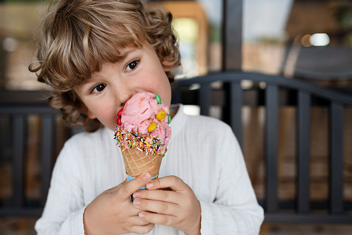 Young child eating colorful ice cream cone, illustrating boomer relatives undermining kids' healthy habits with candies and soda.