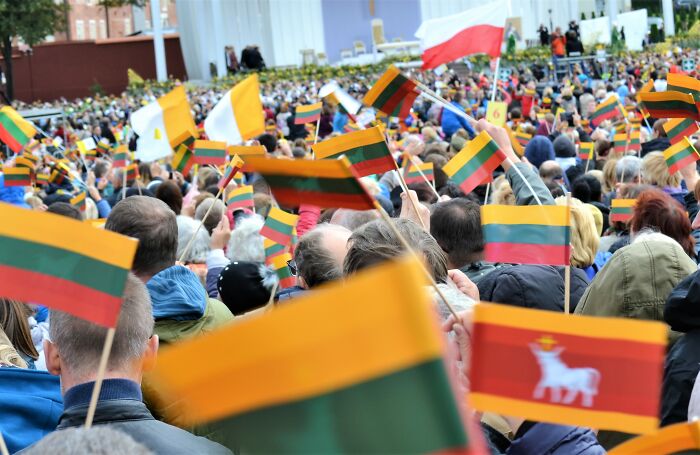 Crowd of European netizens waving Lithuanian flags during an event debunking commonly mistaken facts about their countries.