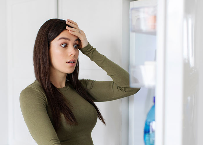 Woman looking shocked while opening fridge, learning sister&rsquo;s friends drank her irreplaceable champagne and she won&rsquo;t forgive it