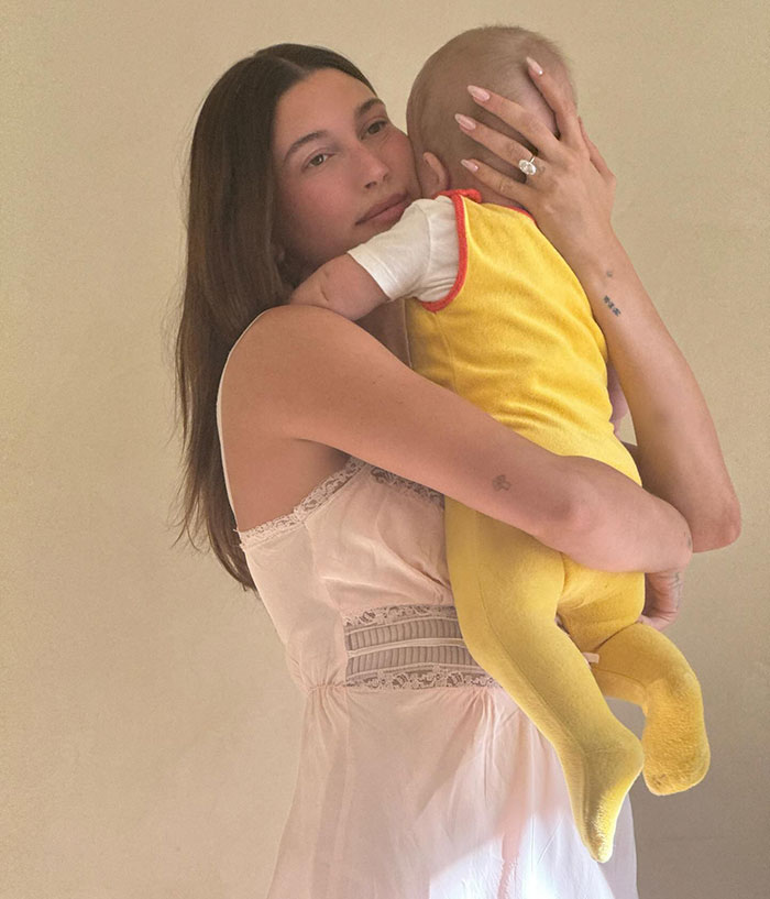 Hailey Bieber holding baby close in soft lighting, relating to Father&rsquo;s Day and revenge on Justin Mother&rsquo;s Day post.