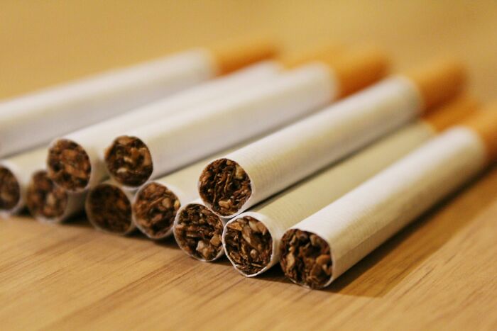 Close-up of unlit cigarettes arranged on a wooden surface, highlighting tobacco content in each cigarette.