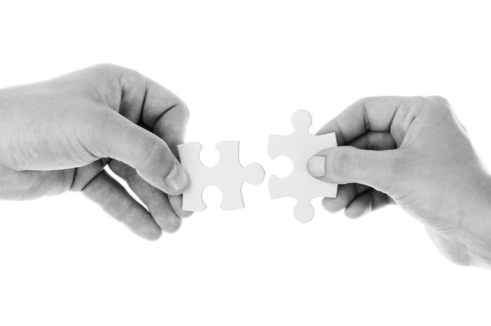 Two hands holding white puzzle pieces, symbolizing connection and common English phrases challenge.