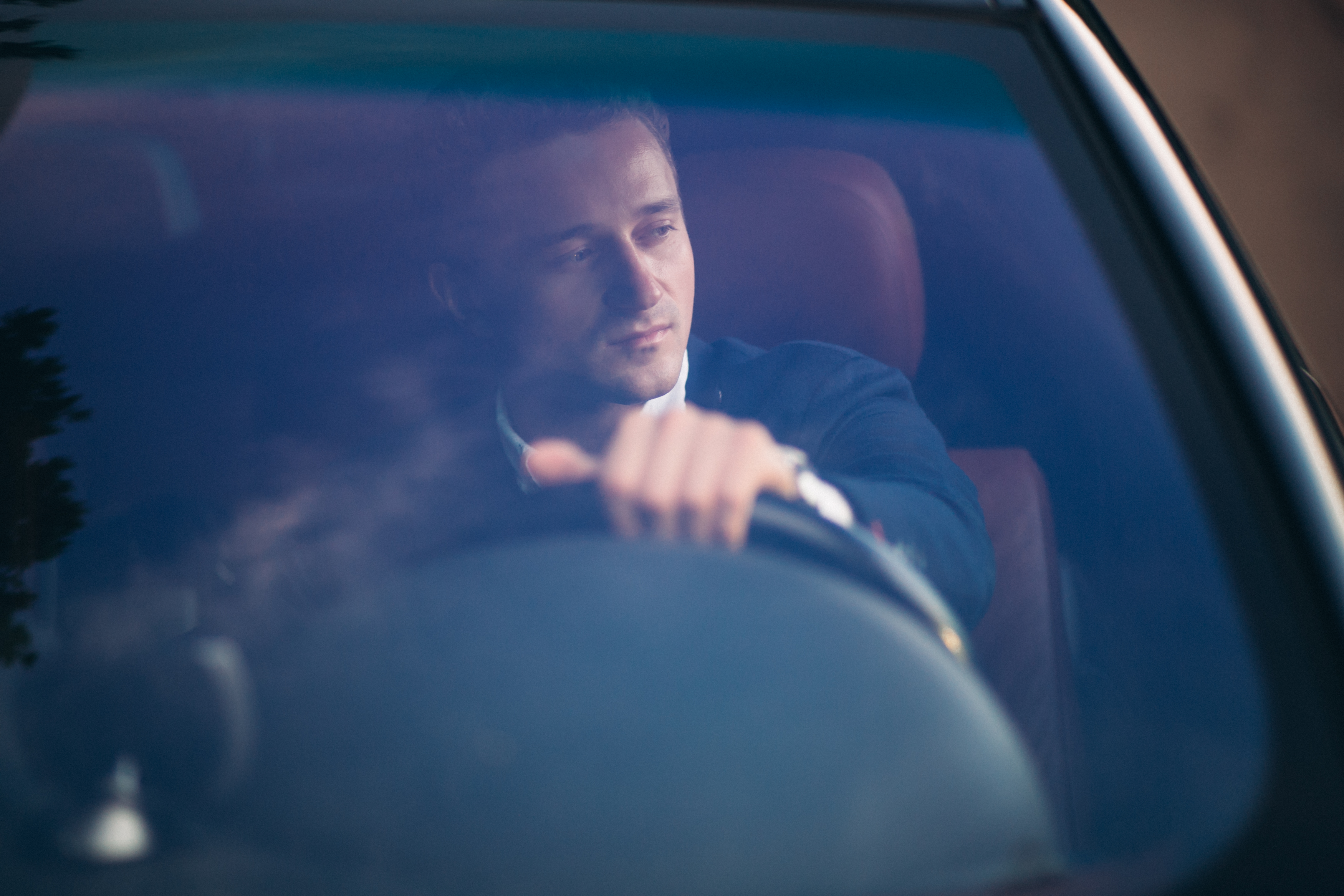 Man focused on safe driving, holding steering wheel inside a car viewed through the windshield on a clear day