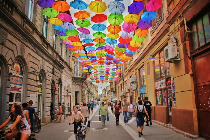 Colorful umbrellas hanging over a European street filled with pedestrians, highlighting common misconceptions about European countries.