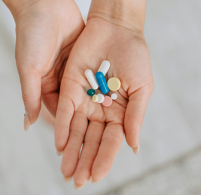 Open hands holding various colorful pills and capsules symbolizing health and wellness myths about targeting fat.