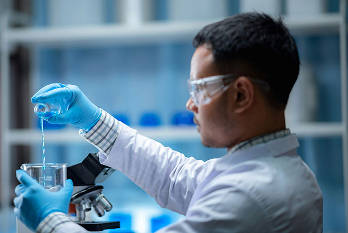 Scientist wearing gloves and goggles conducting lab research related to health and wellness myths about targeting fat.