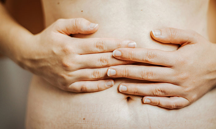 Close-up of hands covering the stomach area, symbolizing the concept of targeting fat in health and wellness.