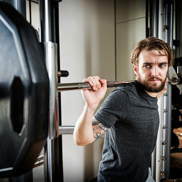 Man with tattoo lifting weights in gym focused on fitness and debunking health and wellness myths about targeting fat