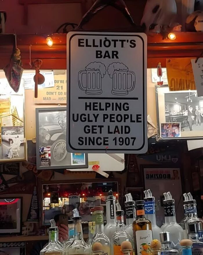 Funny bar sign with two beer mugs humorously claiming to help ugly people get laid, adding chaos to the world with hilarious signs.