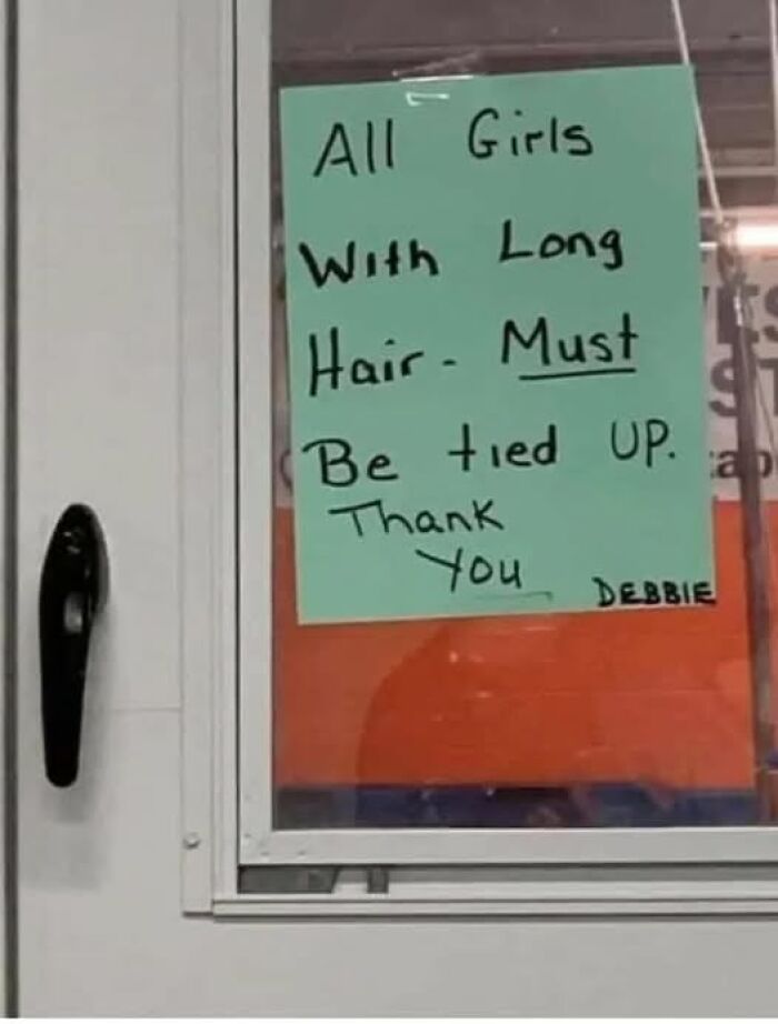Funny sign on a window instructing all girls with long hair to have it tied up, adding chaos to the world.