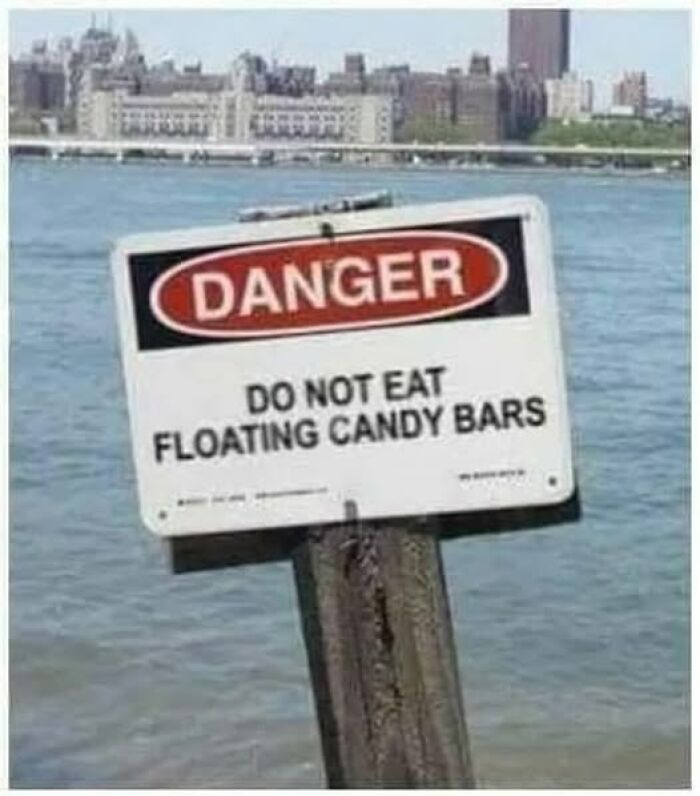 Warning sign by water reading do not eat floating candy bars, a hilarious sign adding chaos to the world.