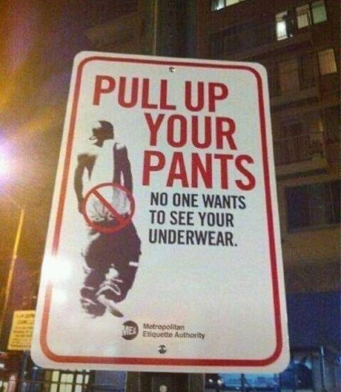 Street sign humorously instructing to pull up pants to avoid showing underwear, adding chaos with hilarious signage.