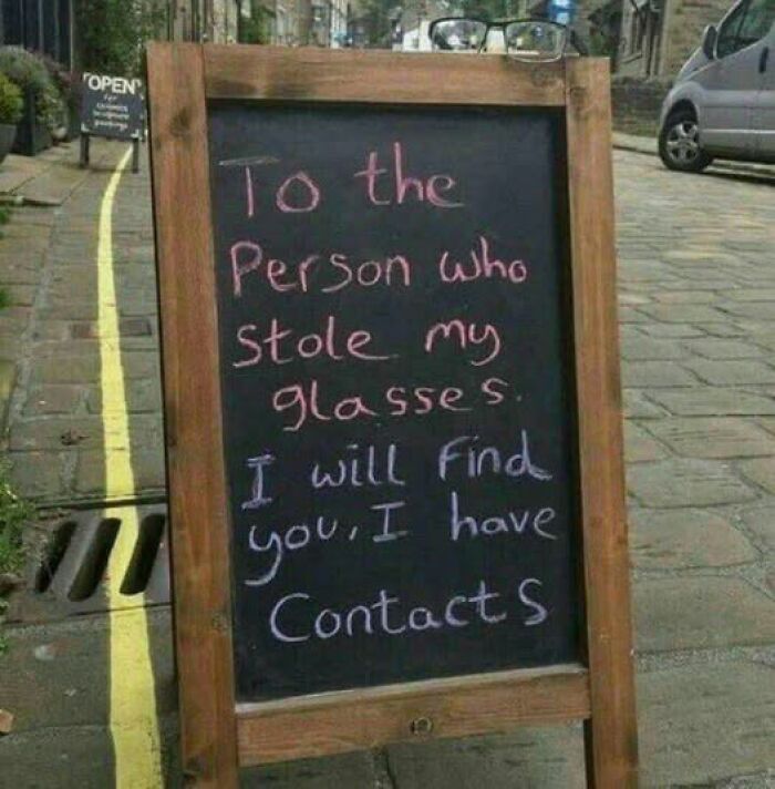 Chalkboard sign with a humorous message about stolen glasses and having contacts, showcasing hilarious signs chaos.