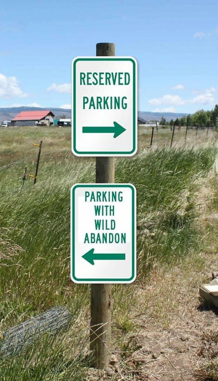 Two parking signs on a post in a field showing reserved parking and parking with wild abandon directions chaotic signs.