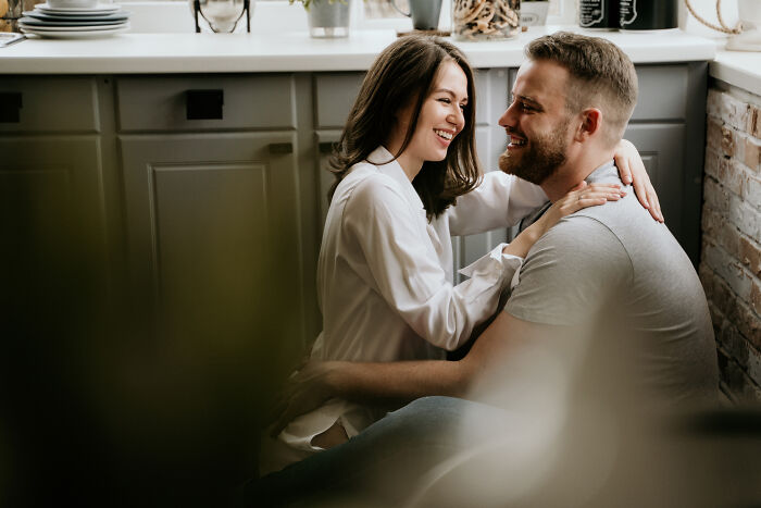 Couple smiling and embracing warmly in a cozy indoor setting, inspired by famous folks from history people would love to call.
