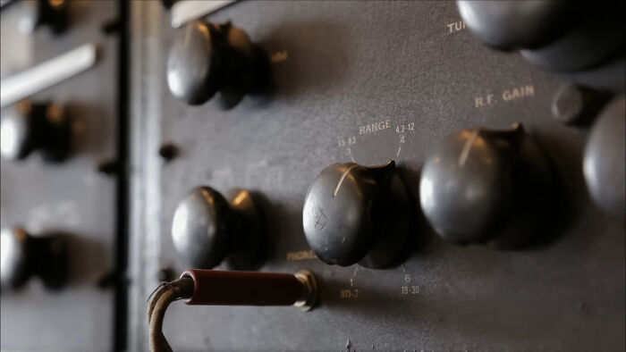 Close-up of vintage radio dials and knobs on a historic communication device with an attached old-fashioned cord.