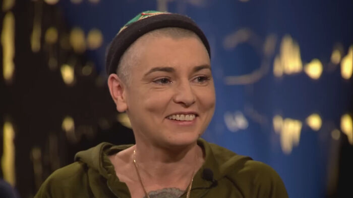 Person smiling and wearing a green hoodie and black beanie in a studio setting, related to history folks people would love to call.