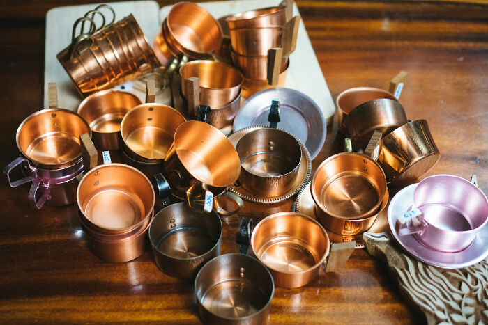 Collection of vintage copper and metal cups arranged on a wooden surface representing historical artifacts and memorabilia.