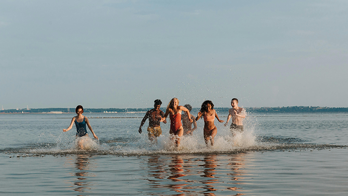 Group of kids running and splashing in the water during a chaotic trip, showcasing misbehaved friends' kids outdoors.