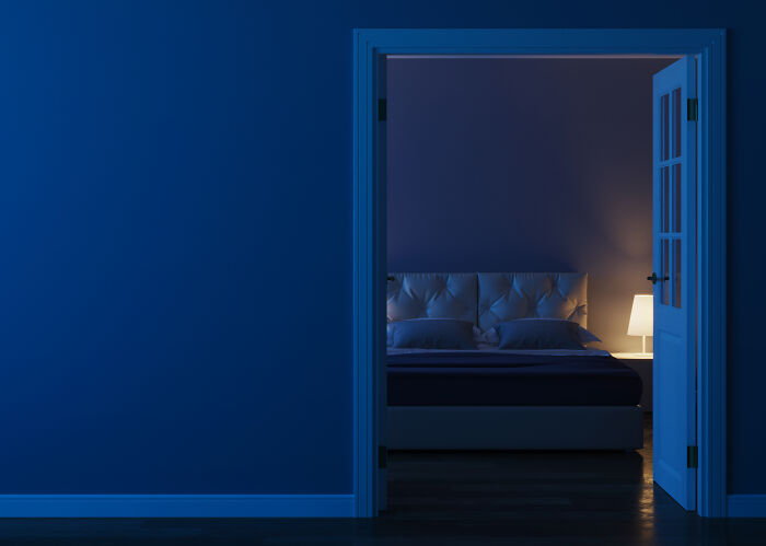 Dimly lit bedroom viewed through open door, illustrating local dangers that are a normal part of life for some people.