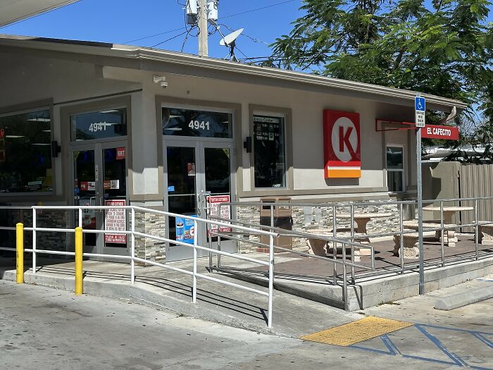 Convenience store exterior with handicap ramp and outdoor seating, illustrating local dangers as a normal part of life.