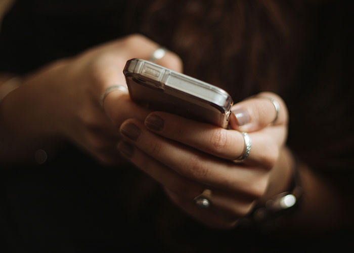 Close-up of hands holding a smartphone, illustrating a pregnant woman proving her eligibility for maternity leave.