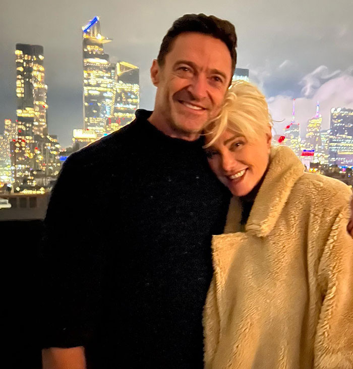 Hugh Jackman smiling with a woman against a city skyline at night amid divorce setback news