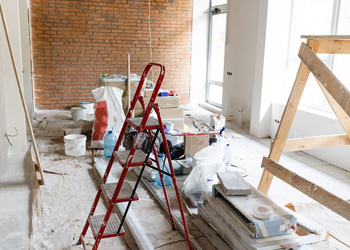 Interior of house under renovation showing moving supplies and a red ladder as a married couple moves houses together.