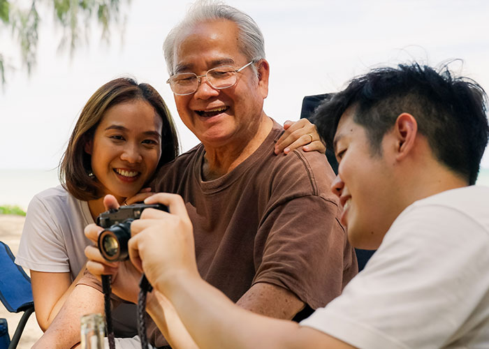 Smiling married couple reviewing photos together outdoors while husband handles camera during house moving preparations.