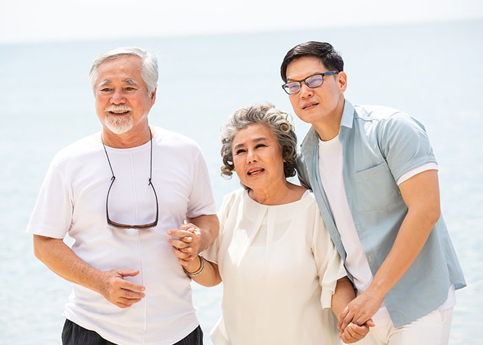 Married couple holding hands by the beach, symbolizing moving houses and the husband leaving tasks for wife to handle.
