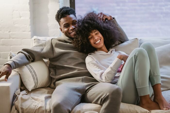 Happy couple relaxing on couch at home, illustrating husband funding teen children in a cozy setting