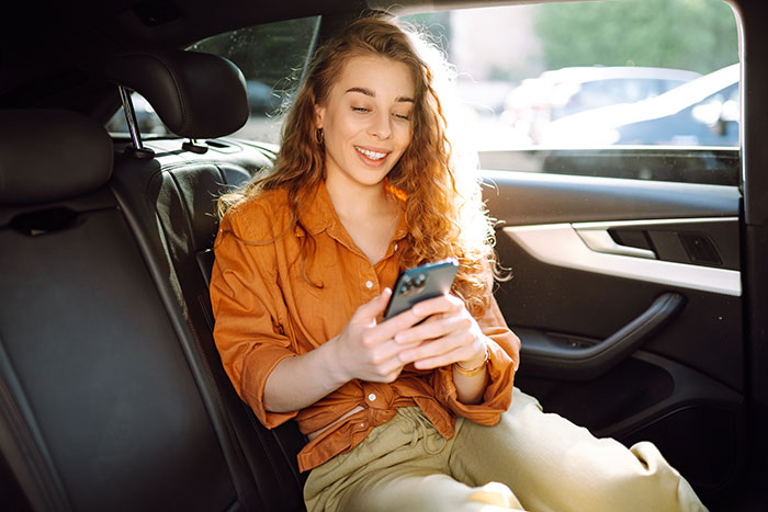 Young woman in a car smiling and texting on her phone, reacting to a man asking for divorce then joking about it. Young woman in a car smiling and texting on her phone, reacting to a man asking for divorce then joking about it.