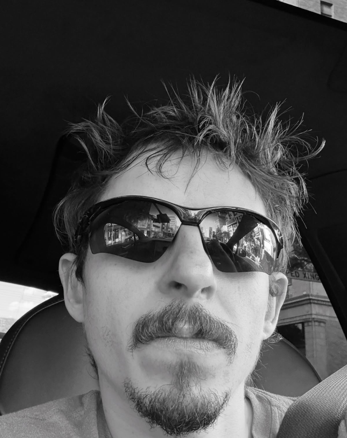 Man with spiked hair and sunglasses in a car, resembling beloved character from Hannah Montana looking exactly the same years later