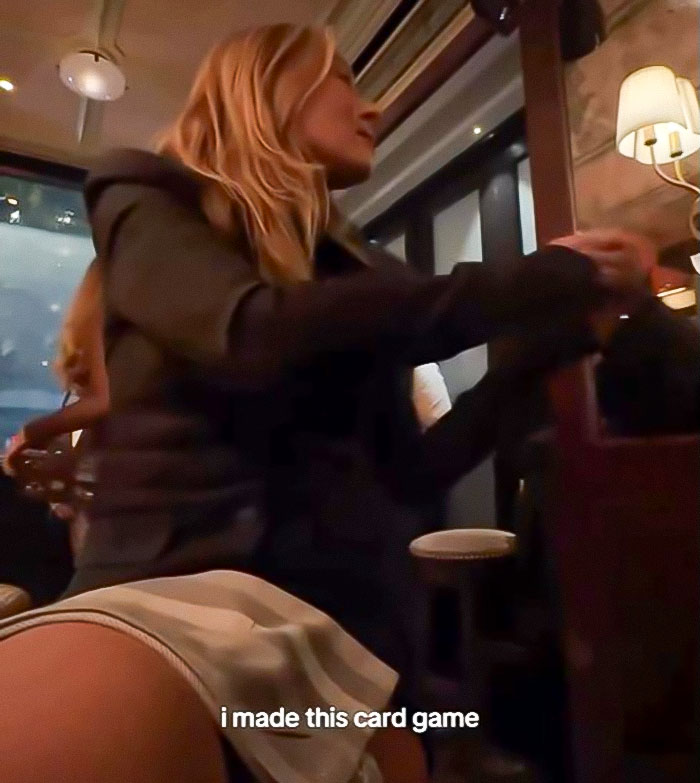 Woman in a dark jacket sitting at a table in a dimly lit room, related to pushy influencer rejected by Taylor Swift.