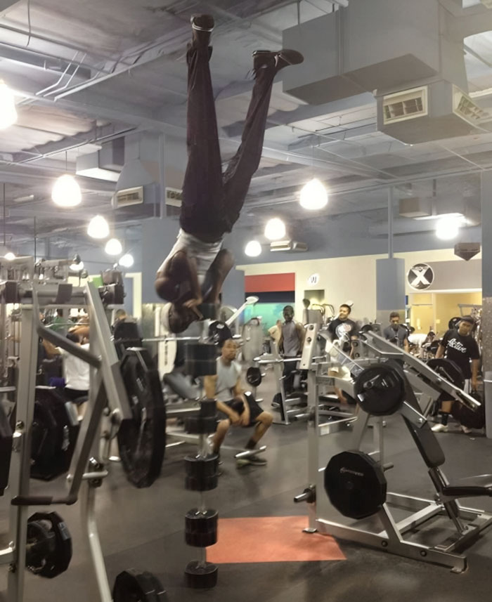 Man unexpectedly falling upside down among gym equipment during annoying gym moments with other people working out nearby