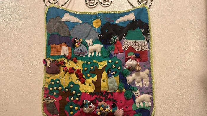 Colorful embroidered fabric art showing animals and houses, an example of unexpected things found in walls in people’s homes.