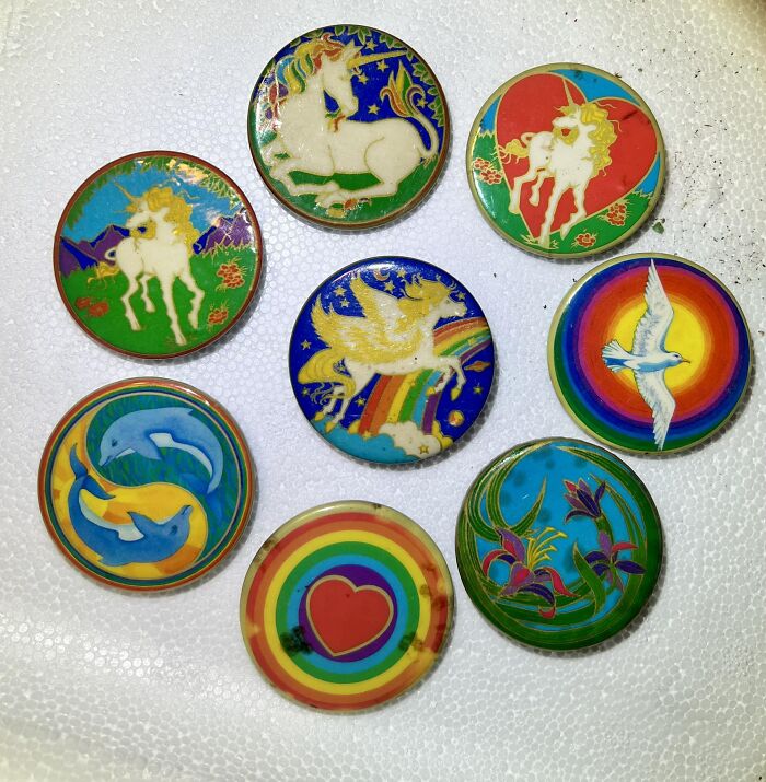 Colorful vintage pins featuring unicorns, dolphins, and rainbows, one of the unexpected things found in walls and hidden places.
