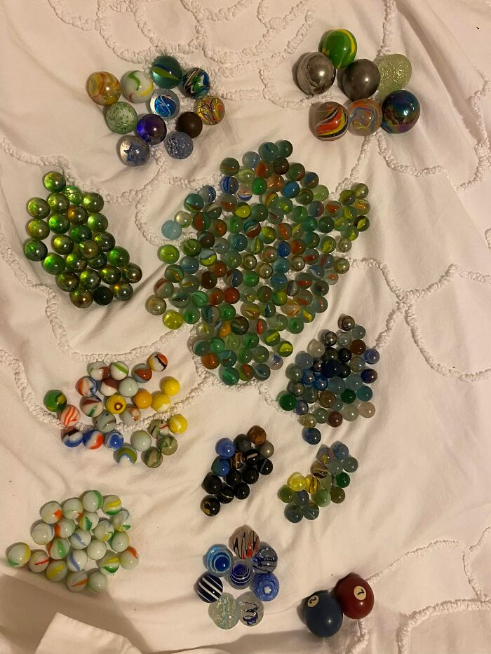 Various colorful glass marbles grouped on a white textured fabric, an unexpected thing found in walls and hidden places.