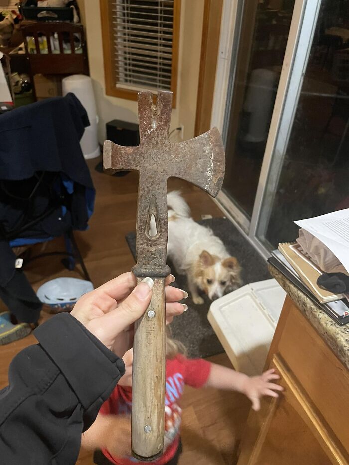 Rusty old axe tool found inside walls and other hidden places in people’s homes, held by hand in a kitchen setting.