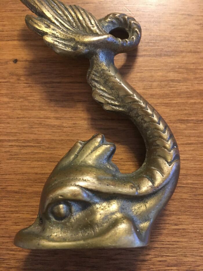 Antique brass dolphin figurine discovered among unexpected things found in walls and hidden places in homes.