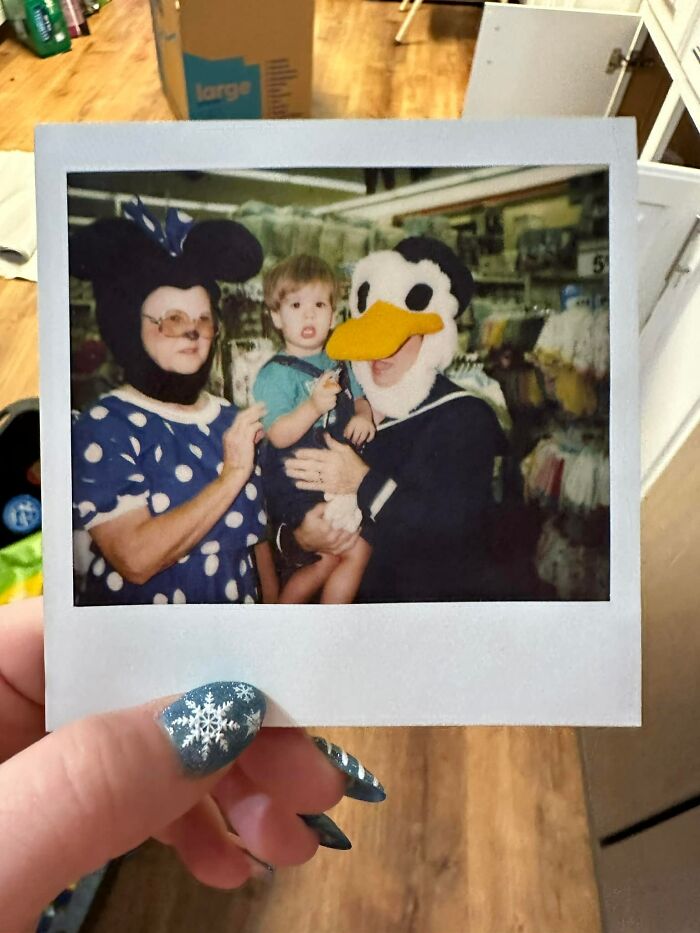 Polaroid photo of two adults in cartoon costumes holding a child inside a home, illustrating unexpected things found in walls.