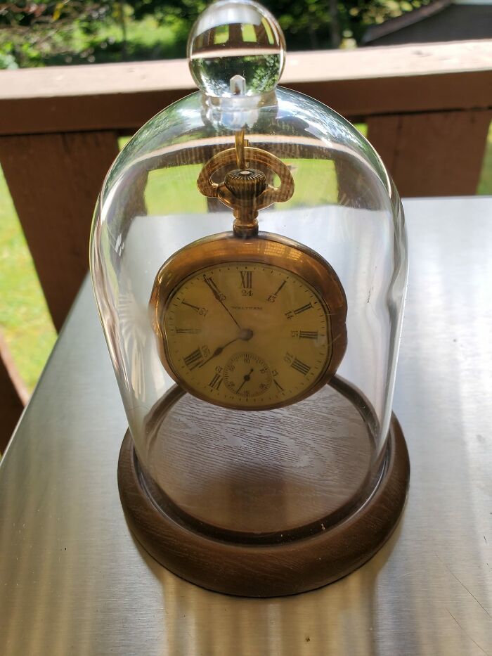 Vintage pocket watch displayed under a glass dome, an unexpected thing found in walls and hidden places in homes.