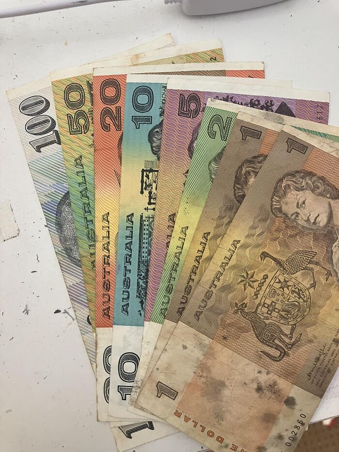 Australian dollar bills found as unexpected things in walls and other hidden places in people’s homes, fanned out on a white surface.