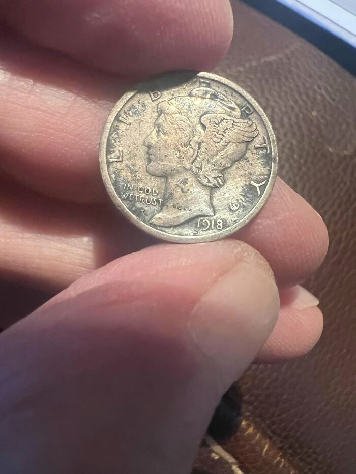 Close-up of a hand holding a 1918 silver coin, an unexpected thing found in walls and hidden places in homes.