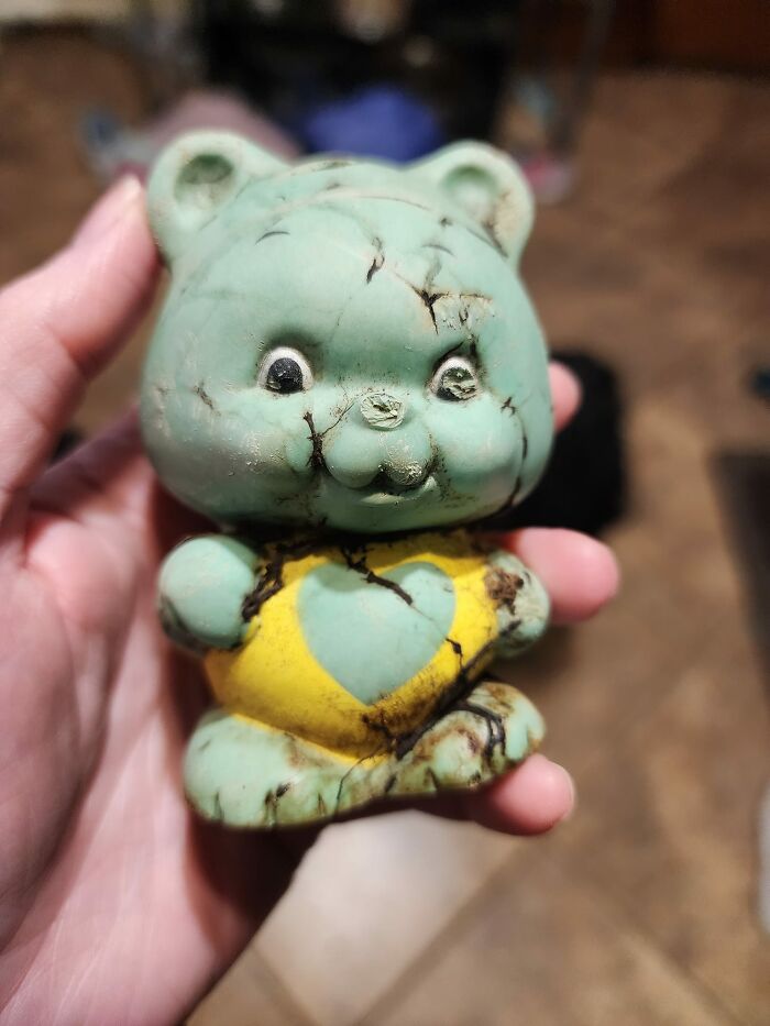 Hand holding a c*****d vintage bear figurine with a heart design, one of unexpected things found in hidden places in homes.