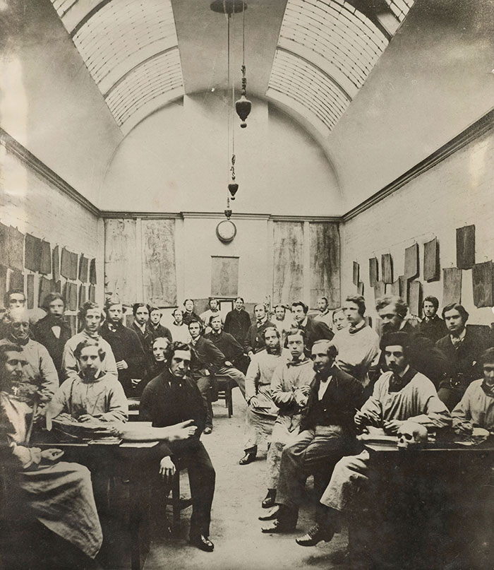 Group of Victorian men posing in a classroom setting, showcasing strange moments from Victorian times that fascinate today.