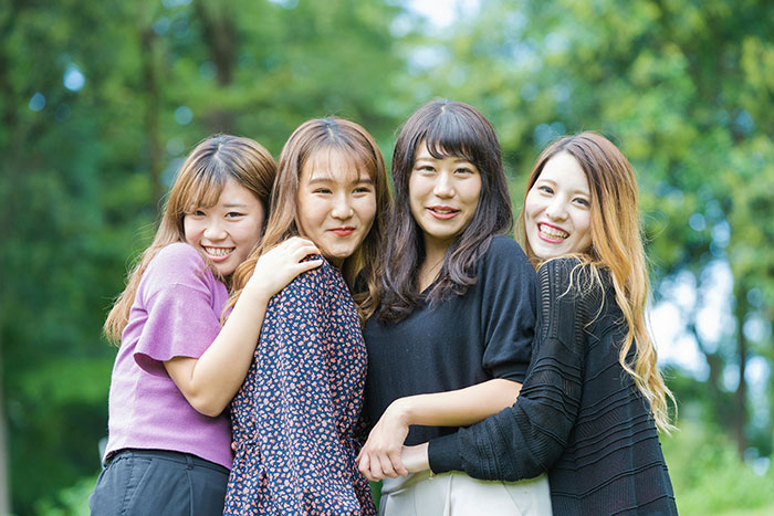 Four young women smiling and posing together outdoors, representing facts to keep the brain active and healthy.