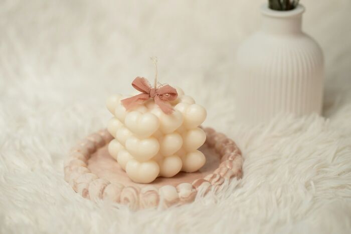 Decorative candle shaped in bubbles with a pink bow, featured in a cozy setting related to industries hit by millennials.