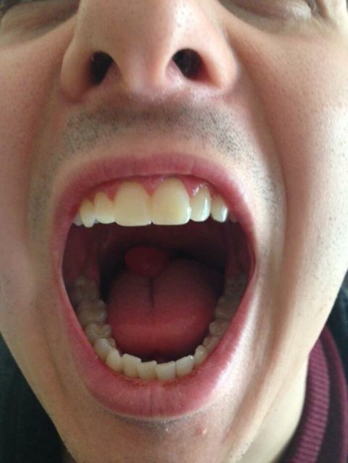 Close-up of human open mouth showing teeth, tongue, and throat, highlighting bizarre and fascinating human body details.