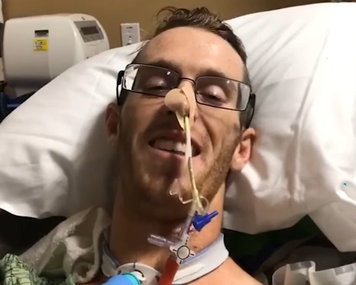 Man with glasses lying in hospital bed with medical tubes after beginner Jiu-Jitsu student injury sparring incident.